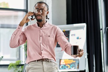 Genç bir Afrikalı Amerikalı uzaktan kumandalı bir işle meşgul. Bir telefon görüşmesini elinde kahveyle dengeliyor..