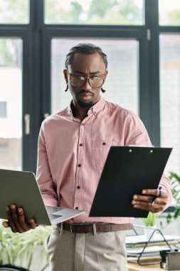 Odaklanmış genç adam, dijital göçebe yaşam tarzını modern bir ofiste sergilerken görevler organize ediyor..