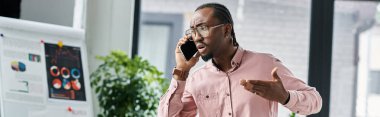 Genç bir Afrikalı Amerikalı, yaratıcı aletlerle çevrili telefonuyla enerjik bir şekilde konuşuyor..