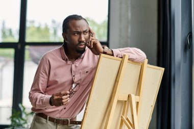 Genç bir Afro-Amerikan adam, bir sehpada sanatsal kavramları düşünerek bir sohbete daldı..