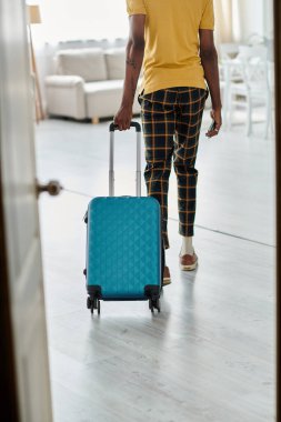 A young african american man rolls his suitcase, ready for a digital nomad adventure in a sleek space. clipart