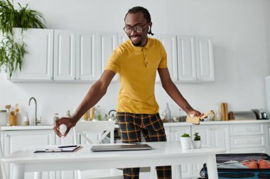 A handsome young man engages in remote work while organizing his space with enthusiasm. clipart