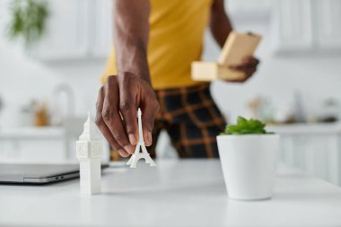 A handsome young man organizes miniature landmarks while working remotely in a bright space. clipart