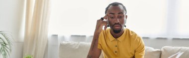 Sarı tişörtlü Afro-Amerikalı genç bir adam parlak ve hoş karşılayıcı bir mekanda işine odaklanıyor..