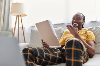 Genç bir Afrikalı Amerikalı, uzak bir yerde, parlak, davetkar bir mekanda çalışırken gülümsüyor..