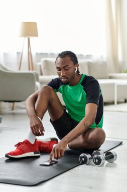 Spor yapmaya odaklanan genç bir adam, spor salonundaki spor ve uzak işleri dengeler..