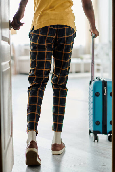A young african american man wearing stylish attire walks out, ready for a new adventure.