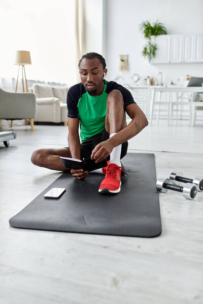 Молодой африканский американец работает удаленно на коврике для йоги, балансируя фитнес и производительность.