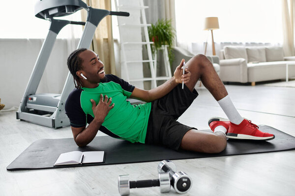 Молодой африканский американец балансирует работу и фитнес в современной гостиной, улыбаясь.