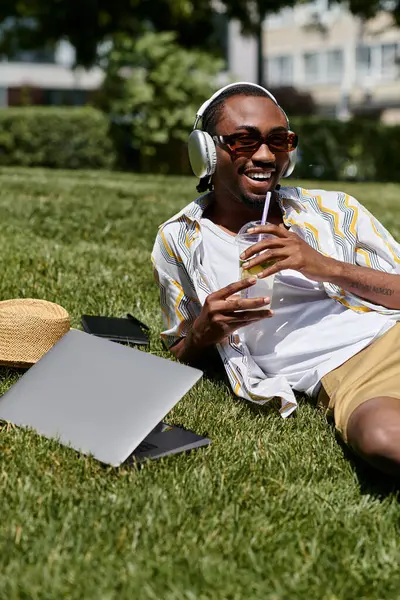 Yakışıklı genç adam parkta dinleniyor, soğuk bir içecek yudumlarken uzak bir işte çalışıyor..