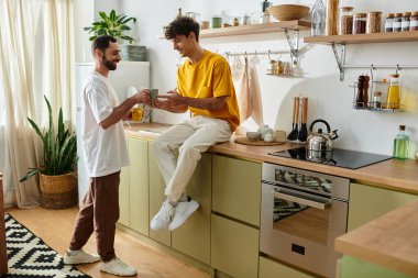 İki adam şık dairelerinde keyifli bir anı paylaşırken birbirlerine eşlik ederler..