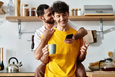 İki adam modern evlerinde sıcak bir anı paylaşıyor, birbirlerine eşlik edip gülüyorlar..