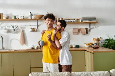 İki erkek, birlikte sakin bir anın tadını çıkarırken modern dairelerinde sevgi dolu bir şekilde kucaklaşırlar..