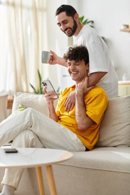 İki adam bir anı paylaşıyor, birbirlerine eşlik ediyorlar ve evde gülüyorlar..