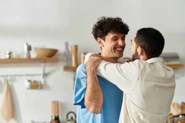 İki erkek, evde sakin bir günün tadını çıkarırken, sevgilerini göstererek neşeyle kucaklaşır..