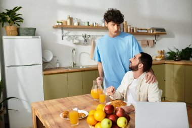 İki adam, sıcak, modern bir mutfakta birbirini seven bir kahvaltıyı paylaşıyor..