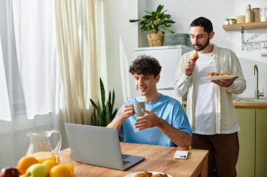 İki erkek kahvaltıdan zevk alır, yemeklerin tadını çıkarır ve şık bir mutfakta birbirlerine eşlik ederler..