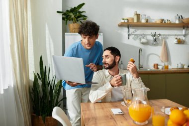 İki erkek birlikte sıcak bir kahvaltıdan zevk alır. Kahkahalarını ve şık mutfaklarında anlarını paylaşırlar..
