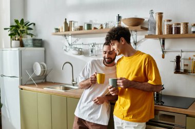 İki adam birlikte sıcak bir anı paylaşıyor, şık bir mutfakta birbirlerine eşlik ediyorlar..