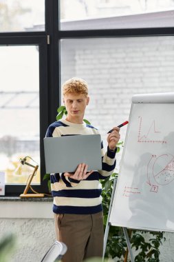 Çizgili kazaklı genç adam modern bir ofiste proje hakkında konuşuyor..