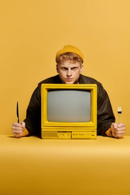 Şık bir adam, parlak bir stüdyo ortamında şık bir kış kıyafeti ve klasik bir televizyonu sergiliyor..