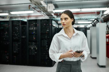 Yüksek teknolojili bir ortamda beyaz gömlekli bir bilişim uzmanı sunucu durumunu gözlemler..