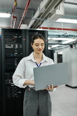 Beyaz gömlekli profesyonel bir kadın sunucu odasında laptopunu kullanıyor..