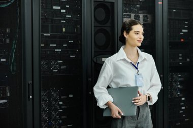 A confident woman in a white shirt manages IT tasks in a high-tech server room. clipart