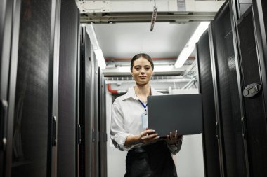 A skilled IT specialist in a white shirt manages data systems in a high-tech server room. clipart