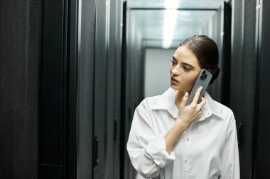 Modern bir sunucu odasında çalışan beyaz gömlekli bir kadın telefonla konuşuyor..