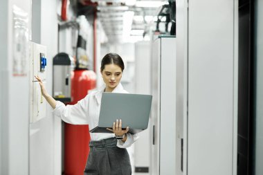 Beyaz gömlekli bir kadın sunucu odasındaki sistemleri izlerken bilgisayarına odaklanır..