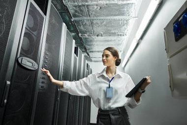 Woman in a white shirt engages with server hardware while maintaining digital security protocols. clipart