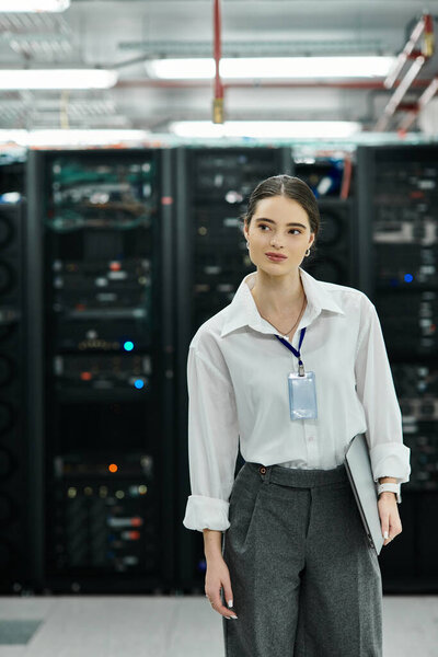 Женщина в белой рубашке усердно работает в современной серверной, контролируя ИТ-операции.