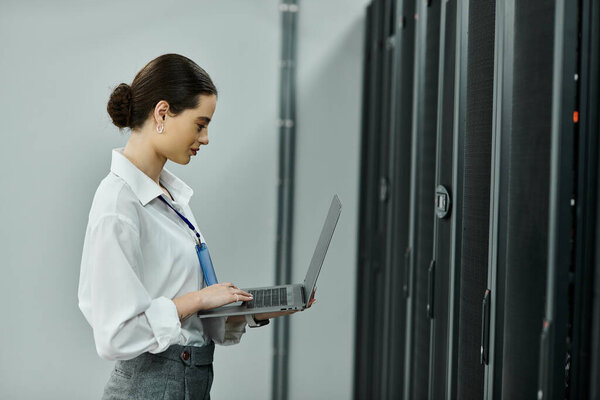 Профессионал в белой рубашке работает на ноутбуке в современной серверной.