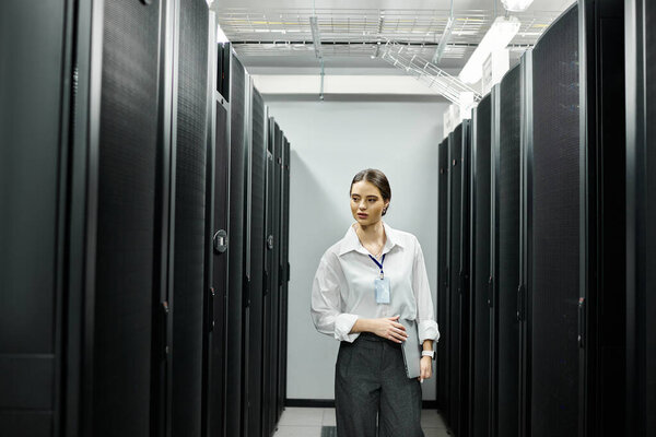 Женщина в белой рубашке взаимодействует с компьютерными системами в гладкой серверной.