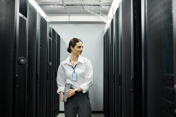 Женщина в белой рубашке усердно работает в современной серверной, управляя системами.