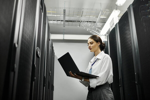 Женщина в белой рубашке усердно работает в современной серверной, управляя компьютерными системами.