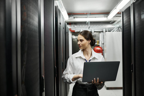 An IT specialist navigates through a modern server room, handling technology with expertise.
