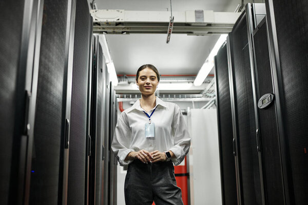 Опытная женщина в белой рубашке работает в высокотехнологичной серверной, обеспечивая сетевую безопасность.