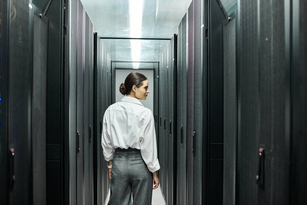 A professional woman in a white shirt works diligently in a data center, overseeing server hardware.
