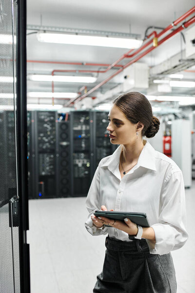 A professional woman in a white shirt is engaged with server hardware in the data center.