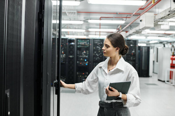 A woman in a white shirt is working diligently in a high-tech server room, focusing on her tasks.