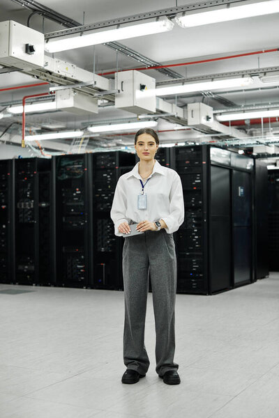 Женщина в белой рубашке усердно работает в загруженной серверной, поддерживая бесперебойную работу систем..