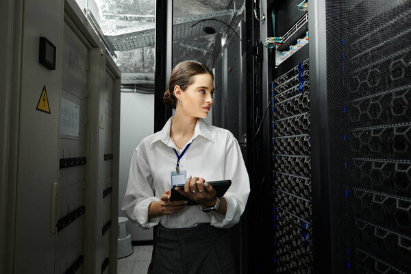 Опытная женщина в белой рубашке контролирует серверные операции и безопасность данных в технологиях.