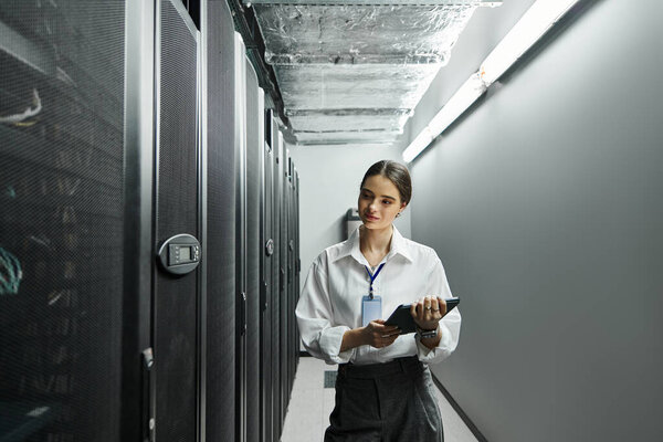 Женщина в белой рубашке усердно работает в гладкой серверной, управляя системами.