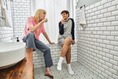 İki erkek doğal ışıkla dolu şık bir banyoda otururken eğlenceli sohbetlerden hoşlanırlar..