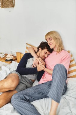 İki erkek, sevgi ve neşe dolu sıcak bir anın tadını çıkarırken şefkatle yataklarında kucaklaşırlar..