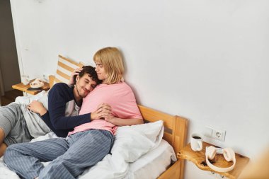 İki erkek, sevgi ve sıcaklıkla çevrili güneşli bir yatak odasında şefkatle kucaklaşır..