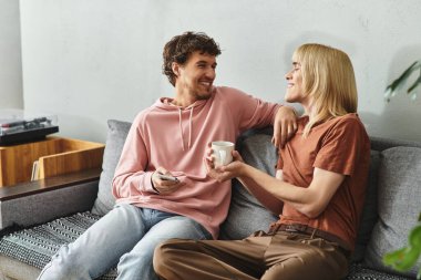 Two men embrace on a couch, enjoying a joyful moment together in a warm setting. clipart