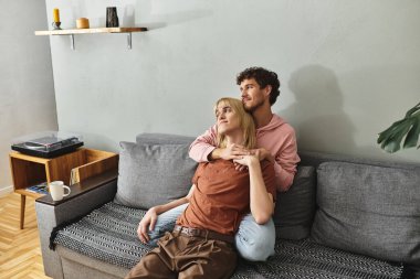 İki erkek, sevgi ve neşe saçan bir kanepede sıcak bir kucaklaşmayı paylaşır..